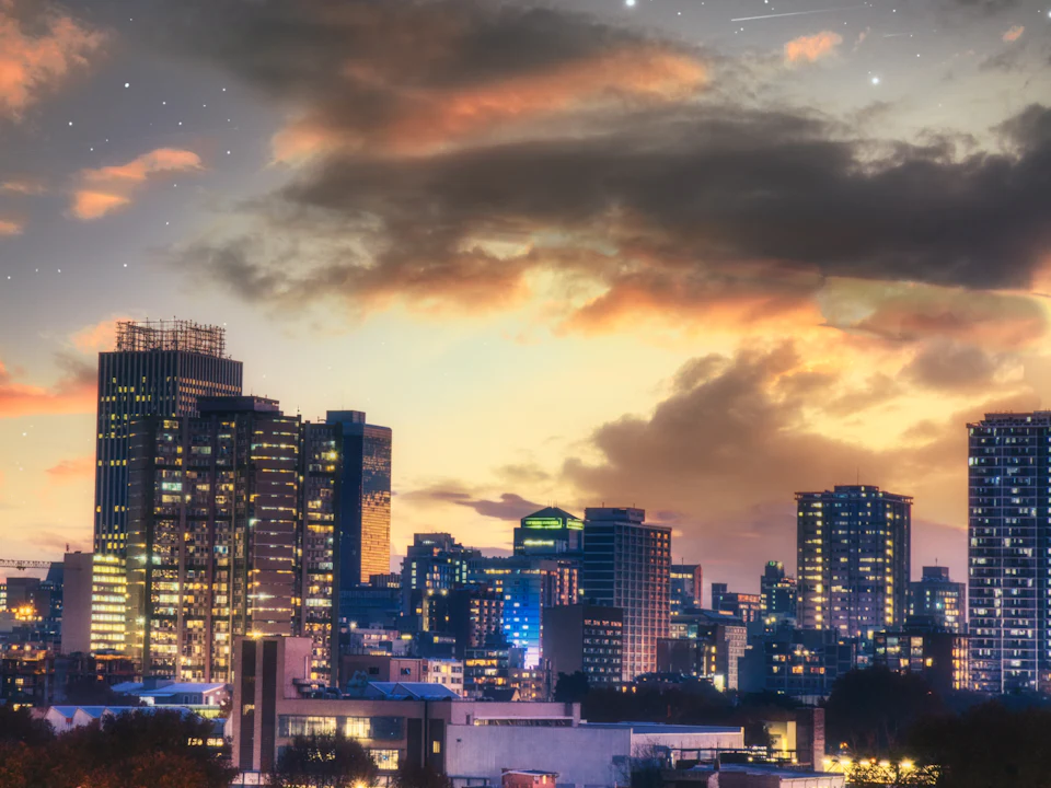 Johannesburg skyline at sunset with office towers lit against a dramatic sky