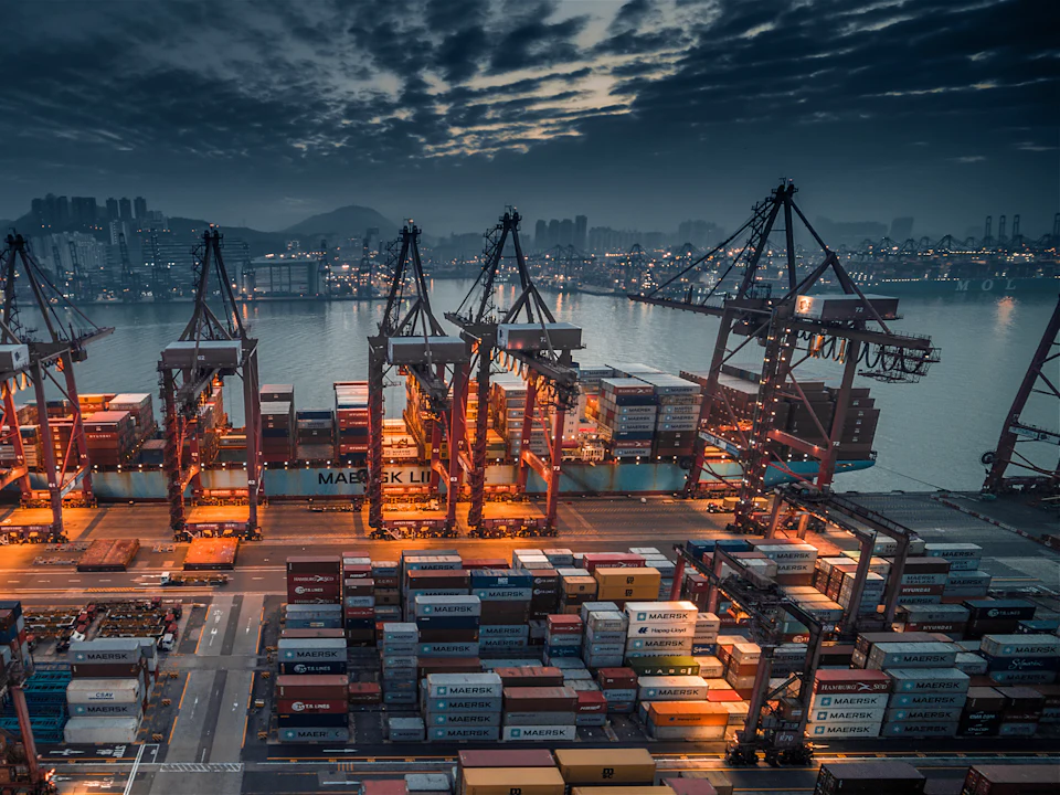 Container port with cranes lit at dusk